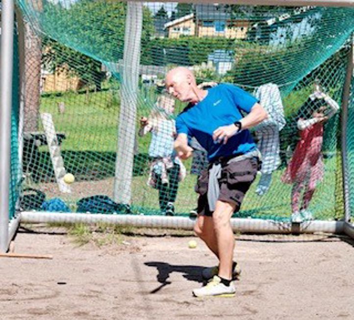 en vaktmester som slår en ball med et balltre