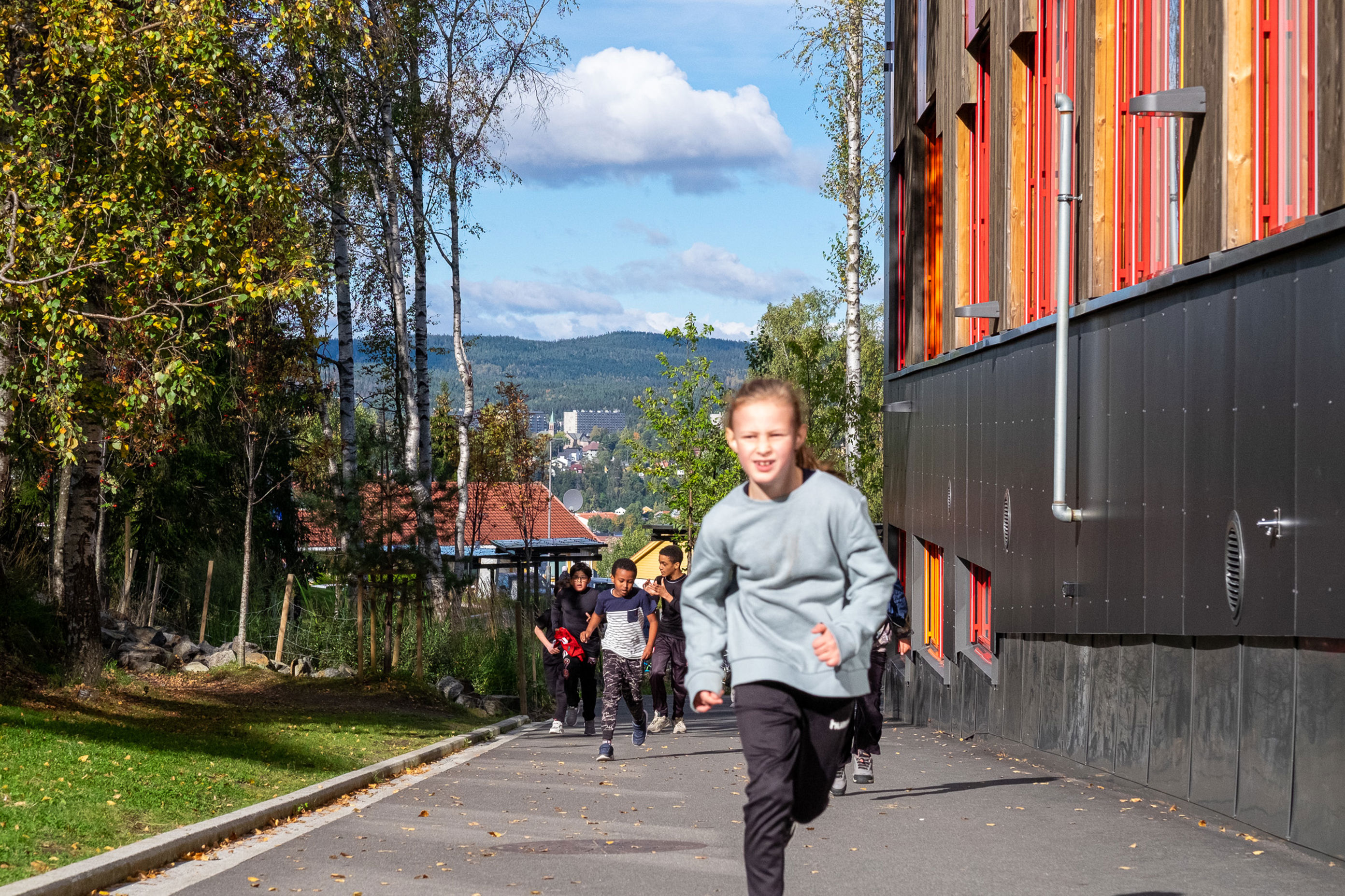 en gruppe mennesker som løper på en sti ved siden av en bygning