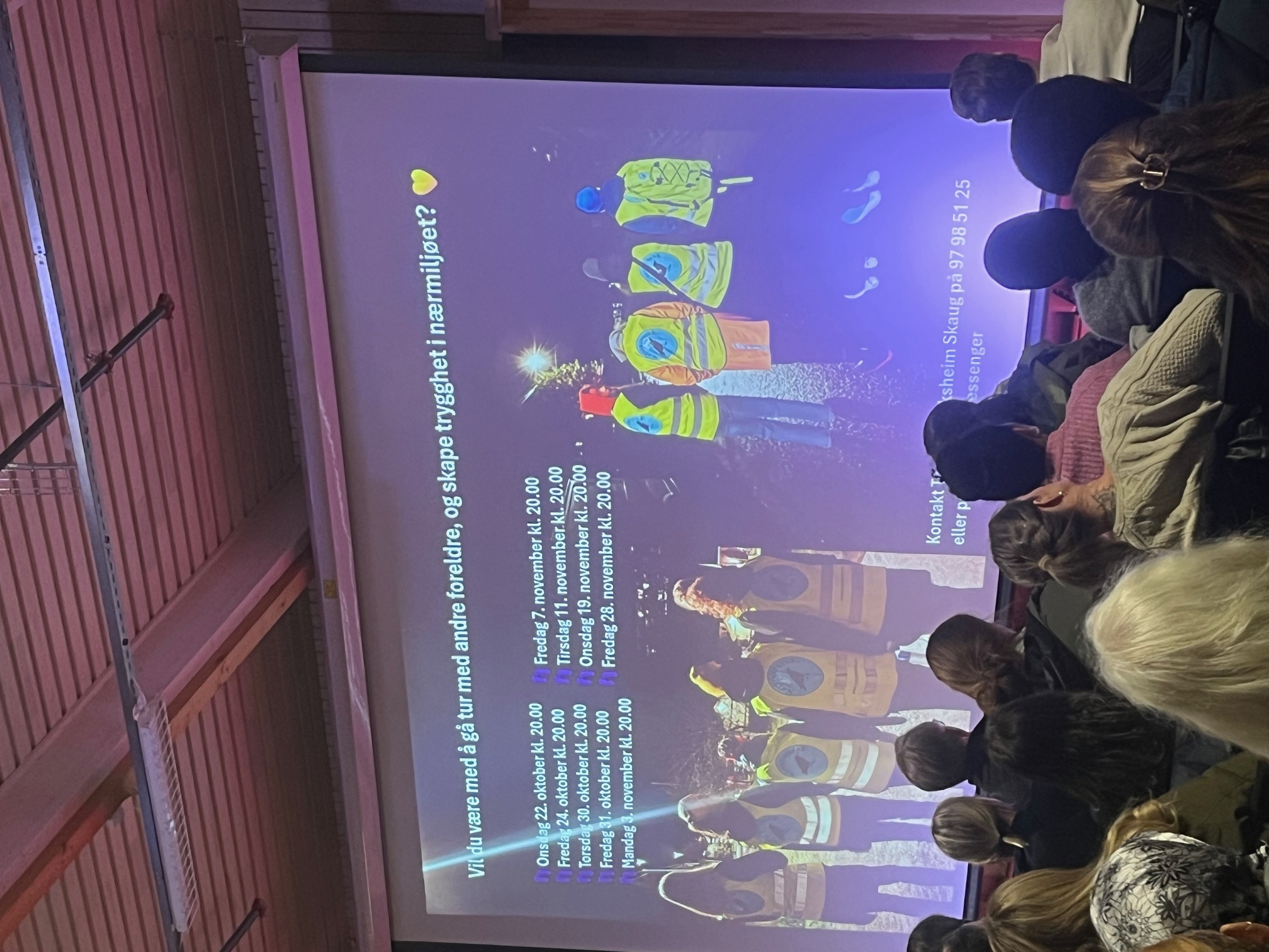 en gruppe mennesker som sitter foran en stor skjerm