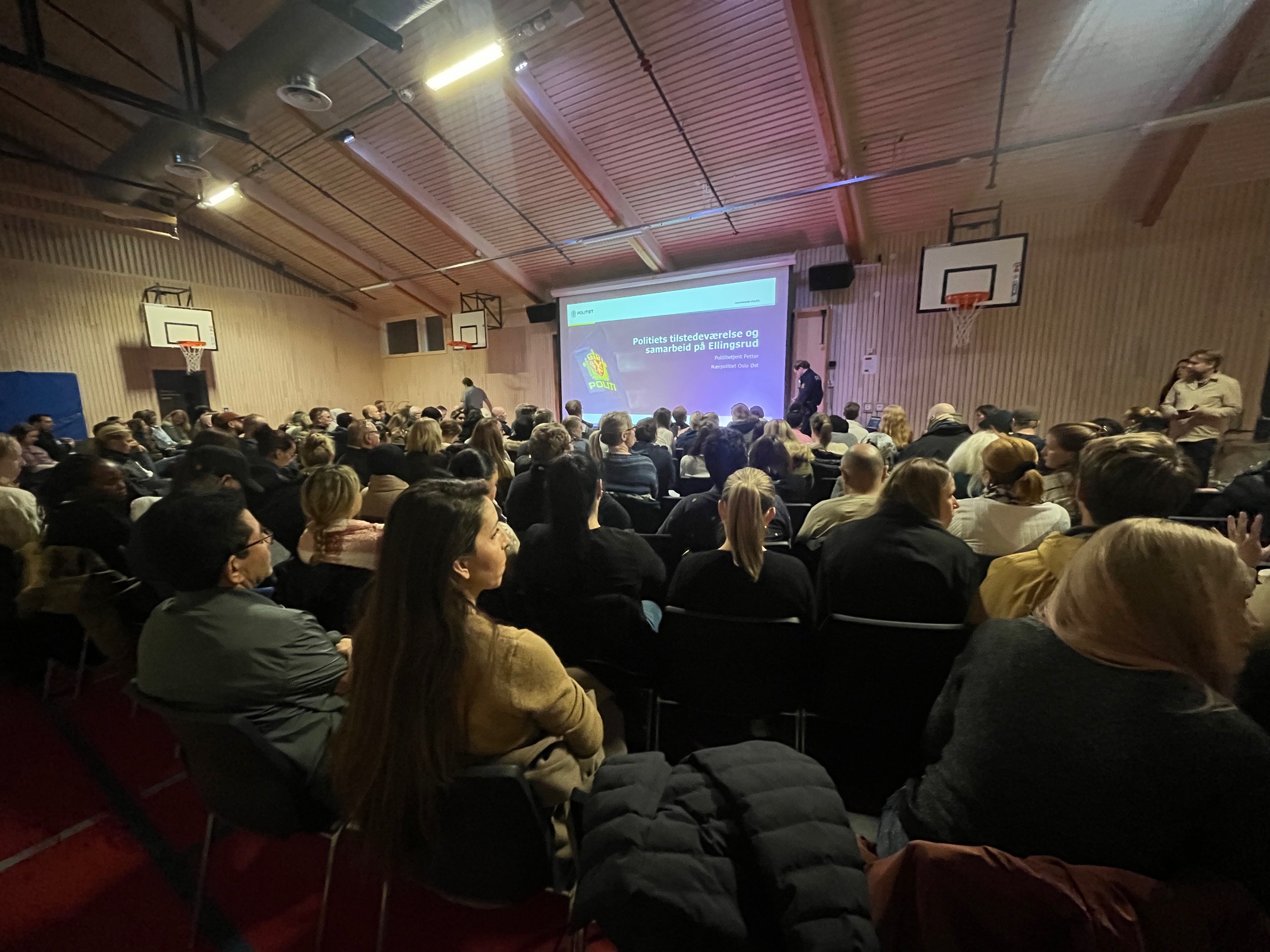 Kirsten Helene Teige en gruppe mennesker som sitter i et rom med en stor skjerm
